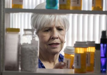 starsza kobieta wybiera lekarstwa z szafki na leki