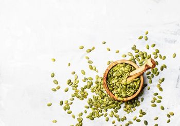 Pestki dyni w niewielkim moździeżu i rozsypane wokól niego 