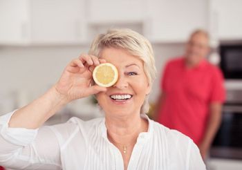 starsza kobieta trzyma w dłoni przekrojoną cytrynę